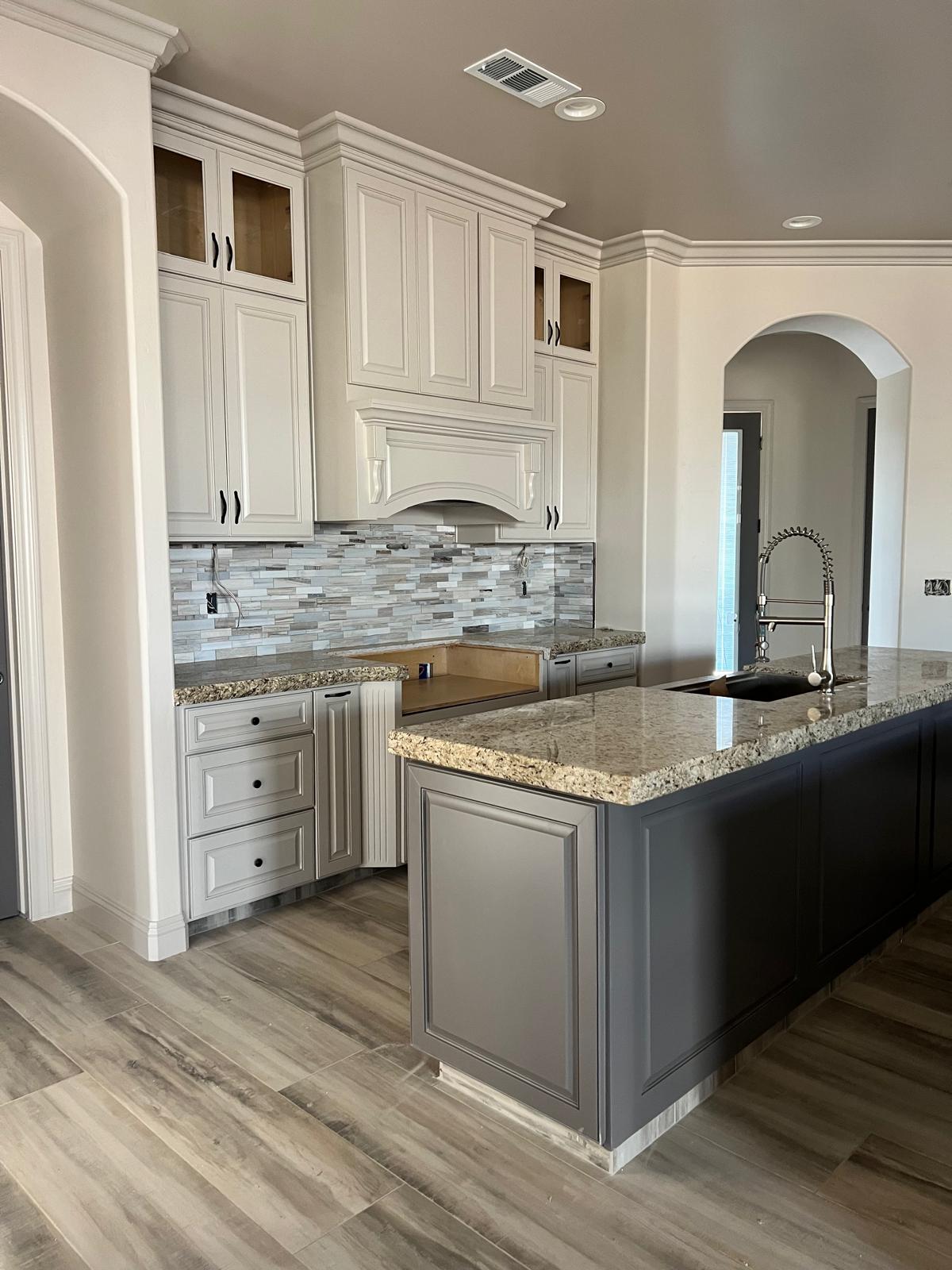 Traditional kitchen with glazed cream raised-panel cabinetry, a gray painted island and granite countertops